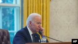 En esta imagen tomada a través de una ventana, el presidente Joe Biden habla por teléfono desde la Oficina Oval de la Casa Blanca en Washington, el jueves 9 de diciembre de 2021. El 2 de abril de 2024 Biden conversó con el presidente de China, Xi Jinping.