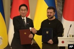 Perdana Menteri Jepang Fumio Kishida, kiri, dan Presiden Ukraina Volodymyr Zelenskyy, saling menyapa usai penandatanganan dokumen bersama di Kyiv, Ukraina, 21 Maret 2023. (Foto: AP)