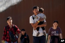 FILE - A group of migrants, including many from China, walk after crossing the U.S. border with Mexico to seek asylum, near Jacumba, California, Oct. 24, 2023.