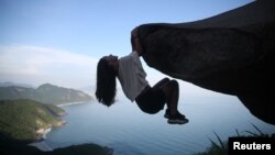 Seorang turis bergelantungan di Telegraph Rock (Pedra do Telegrafo), salah satu tempat paling 'Instagramable' di Rio de Janeiro, Brazil 9 Januari 2024. (REUTERS/Pilar Olivares)