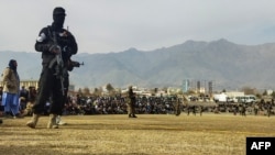 FILE - Taliban security personnel stand guard as people watch a public flogging at a stadium in Charikar, Parwan province, Afghanistan, on Dec. 8, 2022. Four people, including a woman, were similarly flogged recently, Taliban officials said on Oct. 29, 2024.