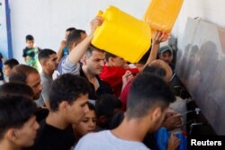 Warga Palestina berebut mengambil air di tengah kekurangan pasokan air minum karena konflik Israel-Paletsina berlanjut di Khan Younis di bagian selatan Jalur Gaza, Minggu, 15 Oktober 2023. (Foto: Mohammed Salem/Reuters)