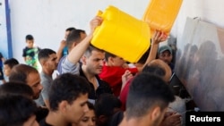 Palestinians gather to collect water, amid shortages of drinking water, as the Israeli-Palestinian conflict continues, in Khan Younis in the southern Gaza Strip, Oct.15, 2023. 