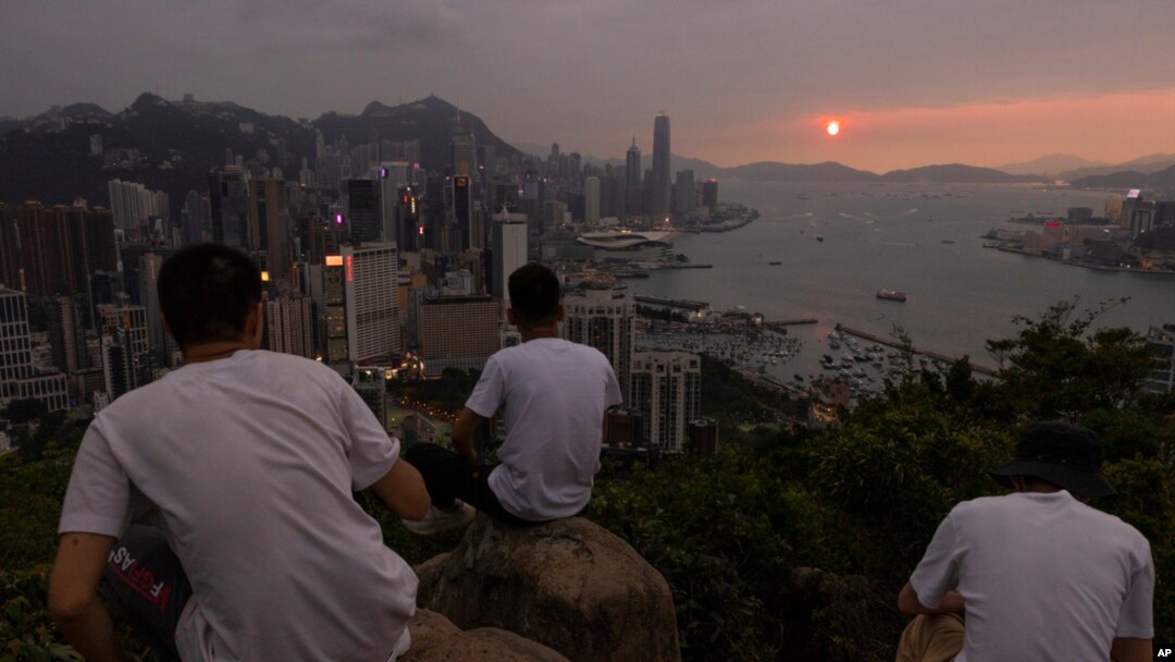 FILE - Mainland Chinese tourists look at sunset from a hill in Hong Kong, April 26, 2023.