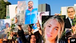Relatives of victims of the deadly 2020 Beirut port explosion react as they hold portraits of loved ones to mark the third anniversary of the massive blast, outside the port of Beirut, Lebanon.