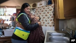 In this photo provided by DigDeep, Shanna Yazzie, project manager for the Navajo Mountain team of DigDeep's Navajo Water Project, left, hugs a client at a home in October 2022, near Navajo Mountain, Ariz.