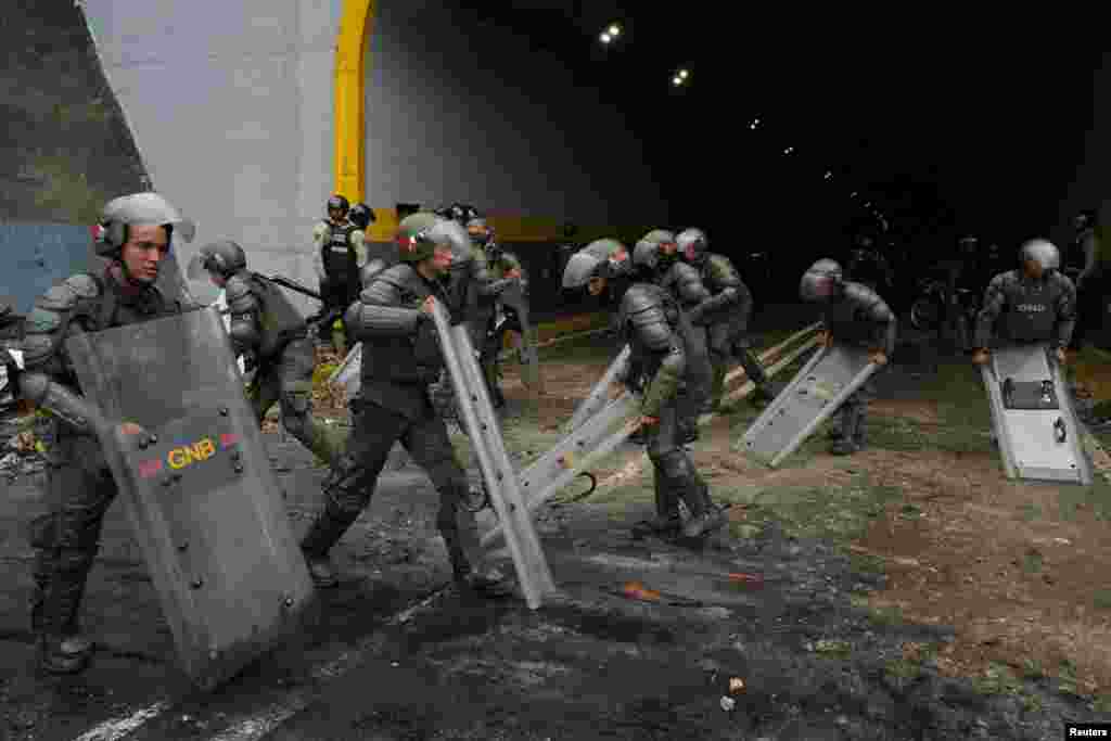 Miembros de la Guardia Nacional Bolivariana de Venezuela usan sus escudos para limpiar una avenida tras protesta en Caracas, el 29 de julio de 2024.&nbsp;