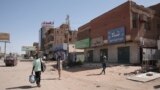 People walk past shuttered shops in Khartoum, Sudan, April 18, 2023.