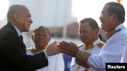 FILE - Cambodia's King Norodom Sihamoni, left, greets Prime Minister Hun Sen at the Independence Monument while attending celebrations marking the 65th anniversary of the country's independence from France, in Phnom Penh, Nov. 9, 2018. 