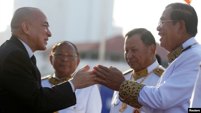 FILE - Cambodia's King Norodom Sihamoni, left, greets Prime Minister Hun Sen at the Independence Monument while attending celebrations marking the 65th anniversary of the country's independence from France, in Phnom Penh, Nov. 9, 2018.