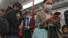 FILE - Commuters wearing face masks check their smartphones on a subway train in Hong Kong, Feb. 7, 2023. Hong Kong lifted its mask mandate March 1, 2023, ending the city's last major restriction imposed during the COVID-19 pandemic.