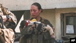 Сержант Морской пехоты США Николь Ги с малышом на руках в международном аэропорту Кабула. Courtesy: U.S. Department of Defense/AP