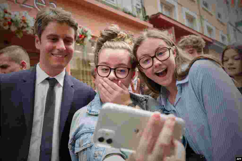 France&#39;s Prime Minister Gabriel Attal (left) poses for a selfie with young people during a campaign visit in Le Mans, northwestern France, ahead of the upcoming parliament elections.