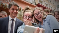 France&#39;s Prime Minister Gabriel Attal (left) poses for a selfie with young people during a campaign visit in Le Mans, northwestern France, ahead of the upcoming parliament elections.