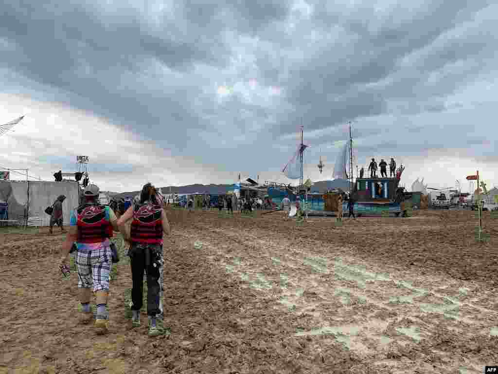 Attendees walk through a muddy desert plain, Sept. 2, 2023, after heavy rains in Nevada&#39;s Black Rock desert.&nbsp;All events at the counterculture festival, which drew some 70,000 people, were canceled after rain tore down structures for dance parties, art installations and other eclectic entertainment.&nbsp;