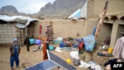 Warga Afghanistan mengumpulkan barang-barangnya di halaman rumahnya yang rusak akibat hujan lebat dan banjir bandang, di Kandahar, Minggu 14 April 2024.