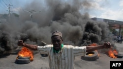 A protester reacts while tires burn in the street during a demonstration following the resignation of Haiti's Prime Minister Ariel Henry, in Port-au-Prince, Haiti, March 12, 2024.