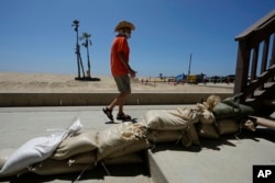 Seal Beach, California, resident Tom Ostrom, walks past a home protected with sandbags on Aug. 18, 2023.