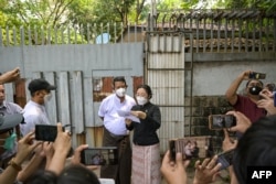 Petugas lelang membacakan pernyataan di luar rumah keluarga pemimpin sipil Myanmar yang ditahan Aung San Suu Kyi di Yangon, 20 Maret 2024. (AFP)