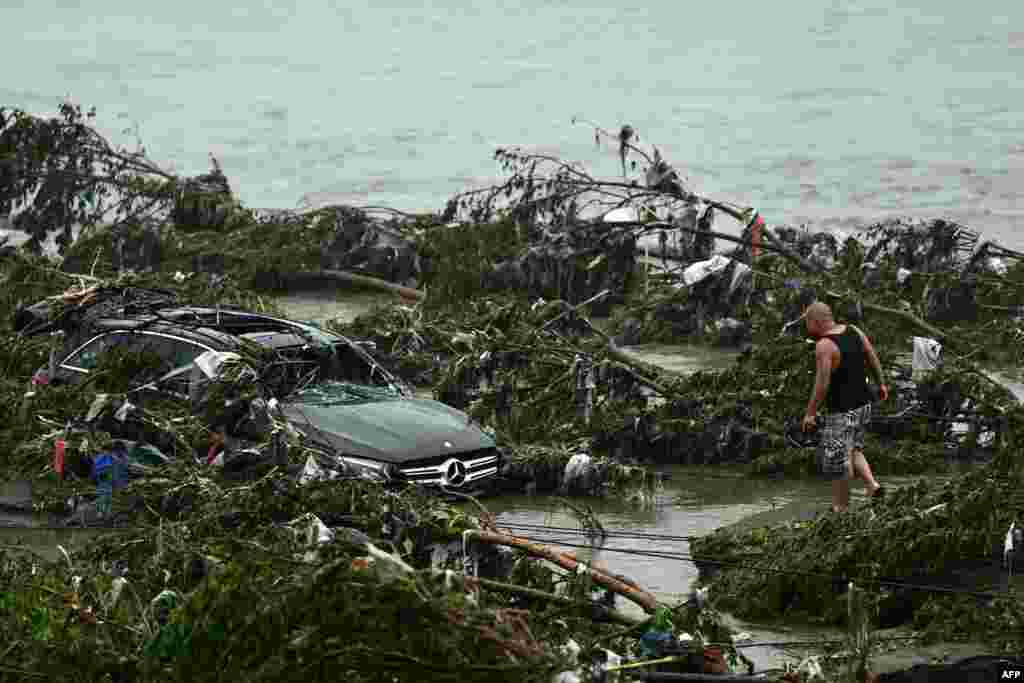 A man looks at a damaged car following heavy rains in the Fangshan district in Beijing, China.