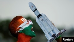 Arun Haryani, an enthusiast with his body painted in tri-colours reacts as he holds up a model of LVM3 M4 which was used in launching of Chandrayaan-3 spacecraft on the eve of its moon landing, in Ahmedabad, India, Aug. 22, 2023.