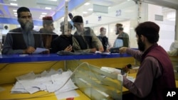 Afghan men wait to receive their passports from the main post office in Kabul, Afghanistan, July 3, 2024. 