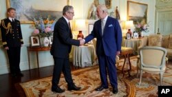 Britain's King Charles III, right, shakes hands with Keir Starmer where he invited the Labour Party leader to become prime minister and to form a new government, following the general election victory for the Labour Party, in London, July 5, 2024.