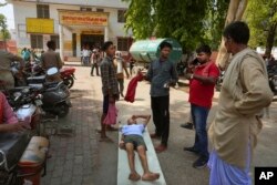 An elderly person suffering from heat related ailment lies on a stretcher waiting to get admitted outside the overcrowded government district hospital in Ballia, Uttar Pradesh state, India, Monday, June 19, 2023.