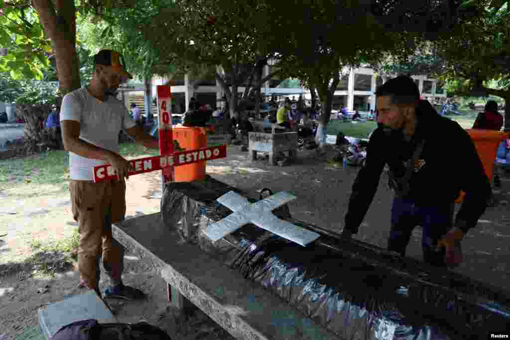 Migrantes colocan un ataúd simulado y una cruz de madera como forma de protesta, durante una pausa en Villa Comaltitlán, en Chiapas.