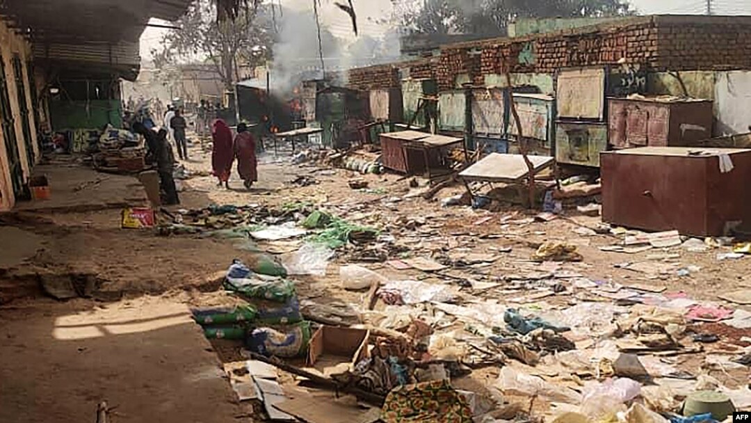 Orang-orang berjalan di sekitar benda-benda yang berserakan di pasar El Geneina di ibu kota Darfur Barat di tengah pertempuran antara pasukan dua jenderal yang bersaing di Sudan, Sabtu, 29 April 2023. (Foto: AFP)