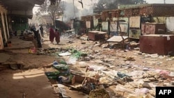 Orang-orang berjalan di sekitar benda-benda yang berserakan di pasar El Geneina di ibu kota Darfur Barat di tengah pertempuran antara pasukan dua jenderal yang bersaing di Sudan, Sabtu, 29 April 2023. (Foto: AFP)