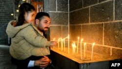 A man with a child light candles during the Easter mass at the Armenian church Surp Giragos, in Diyarbakir, southeastern Turkey, on April 9, 2023.