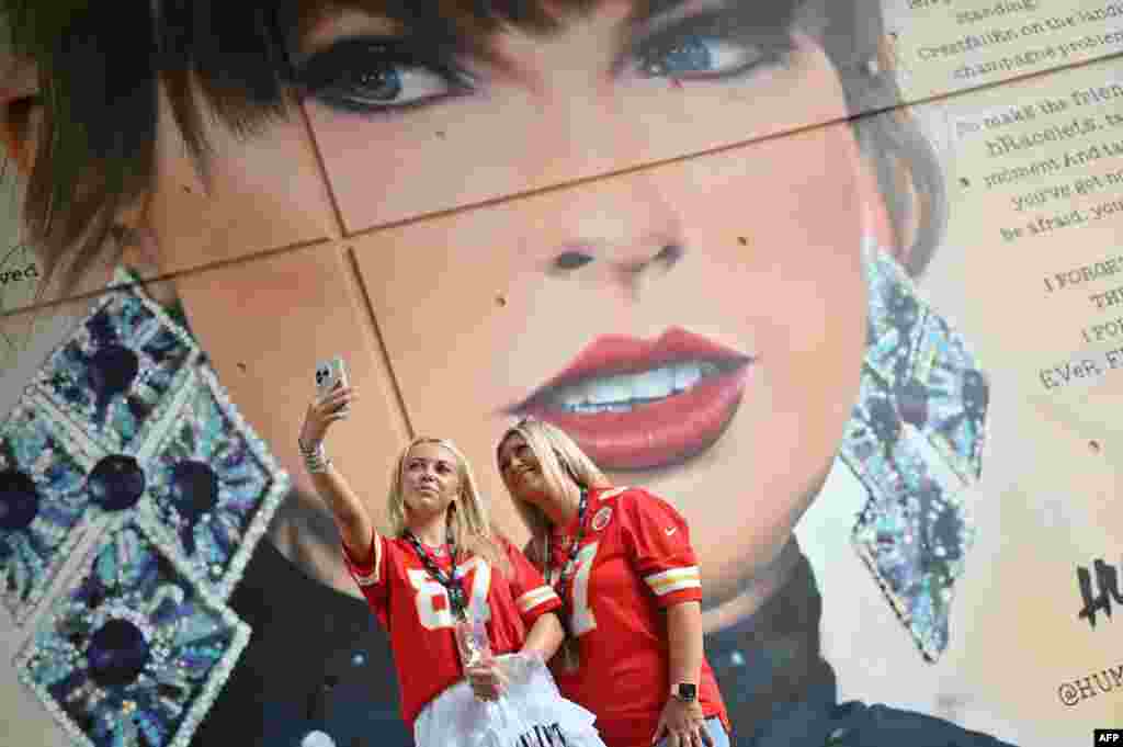 Dua penggemar megabintang AS Taylor Swift berpose untuk foto swafoto di samping mural sang penyanyi yang dibuat oleh seniman jalanan MurWalls, di luar Stadion Wembley di London, menjelang konser Swift di stadion tersebut. (AFP)&nbsp;