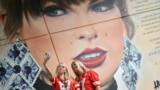 Fans of U.S. megastar Taylor Swift pose for a selfie photograph next to a mural of the performer created by street artists MurWalls, outside Wembley Stadium in London, ahead of the first of five concerts at the stadium.