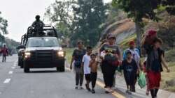 ARCHIVO - Un convoy de soldados de la Guardia Nacional pasa junto a migrantes que caminan hacia el norte por el costado de la carretera en Villa Comaltitlán, estado de Chiapas, sur de México, el 27 de diciembre de 2023.