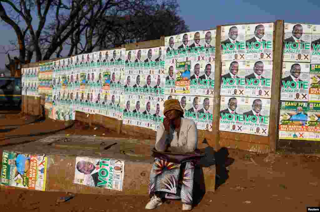 Local resident Linah Shanga sits in front of election posters, ahead of the presidential elections, in Mbare township, in Harare, Zimbabwe.