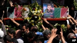 Mourners reach out to the flag-draped coffins of Revolutionary Guard members killed in an airstrike widely attributed to Israel that destroyed Iran's Consulate in Syria on Monday, in a funeral procession in Tehran, Iran, on April 5, 2024.