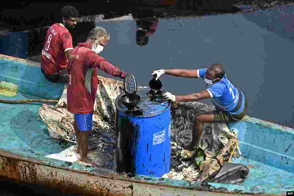 Workers collect oil after it spilled over the backwater at Ennore creek in the aftermath of Cyclone Michaung, on the outskirts of Chennai, India.