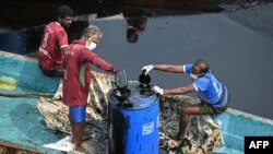 Workers collect oil after it spilled over the backwater at Ennore creek in the aftermath of Cyclone Michaung, on the outskirts of Chennai, India.