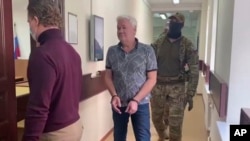 FILE - In this handout photo taken from video released by Lefortovo District Court, Robert Shonov walks to the court room in Moscow, Russia, May 18, 2023.