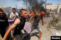 People carry a casualty at the site of an Israeli strike at the Al-Mawasi refugee camp, in Khan Younis, the southern Gaza Strip, on July 13, 2024. (Hatem Khaled/Reuters)