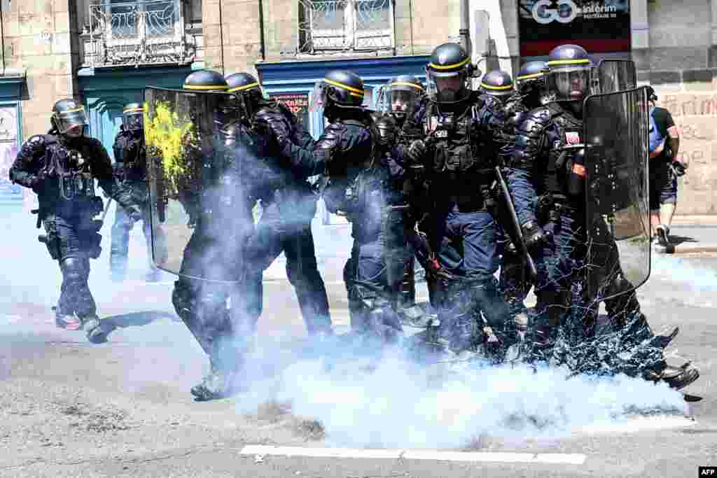 French gendarmes stand in tear gas during confrontations on the sidelines of a demonstration on the 14th day of action after the government pushed a pensions reform through parliament without a vote, in Nantes, western France.