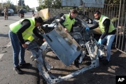Civil defense workers remove parts of a destroyed car in the southern town of Bazouriyeh, Lebanon, Jan. 20, 2024. An Israeli drone strike on the car near the Lebanese port city of Tyre killed two people, the state-run National News Agency reported.