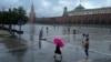 FILE - People with umbrellas walk under the rain through Red Square in Moscow, July 22, 2024. A U.S. citizen was detained on Aug. 12, 2024, in Moscow for allegedly attacking a police officer.