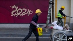 工人推着小车路过上海一家正在修建的商店。（2023年11月25日）