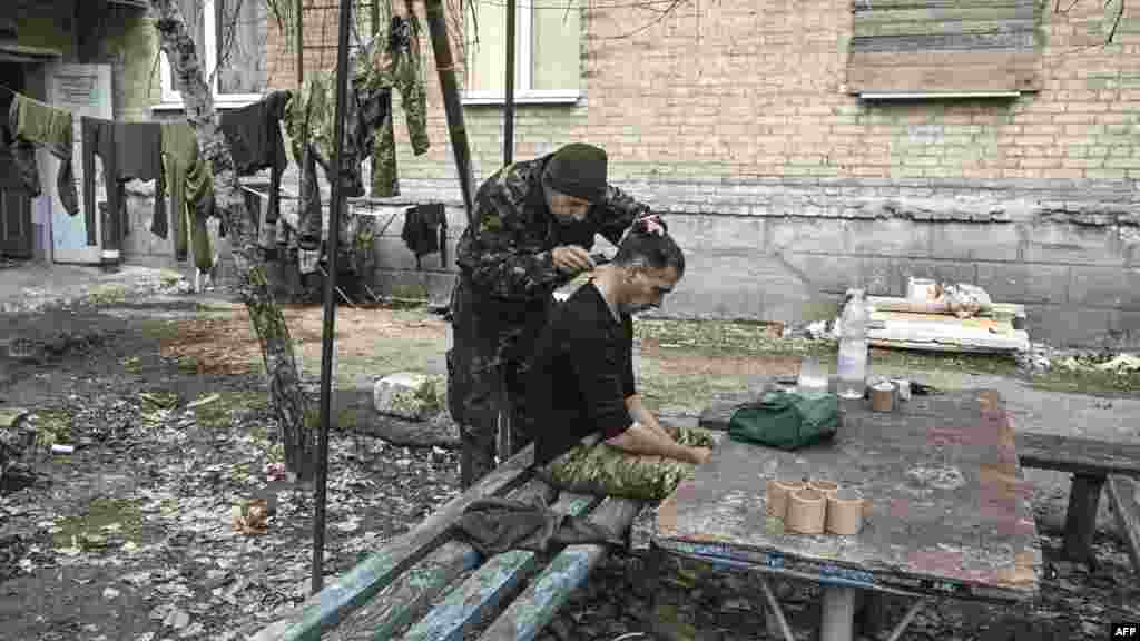 Urush sharoitida askarlar bir-biriga sartaroshlik qilmoda. Baxmut, Ukraina.