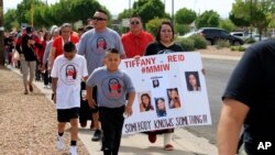 Deiandra Reid holds a sign to bring attention to her sister Tiffany Reid, who went missing 20 years earlier, as dozens of people participate in Missing and Murdered Indigenous Persons Awareness Day in Albuquerque, New Mexico, May 5, 2024. 