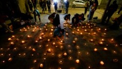 Orang-orang menyalakan lilin untuk mengenang tiga polisi yang tewas di depan markas polisi Chili di Santiago, Chili, Sabtu, 27 April 2024. (AP/Esteban Felix)