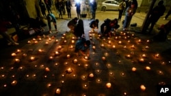 People light candles during a vigil for three police officer in front of Chile's police headquarters in Santiago, Chile, Saturday, April 27, 2024.