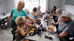 Waitress Kelly Houde, left, fills coffee cups for senior citizens having breakfast as part of the Meals on Wheels "Dine Out Club" at the White Birch Cafe in Goffstown, New Hampshire, July 19, 2023.